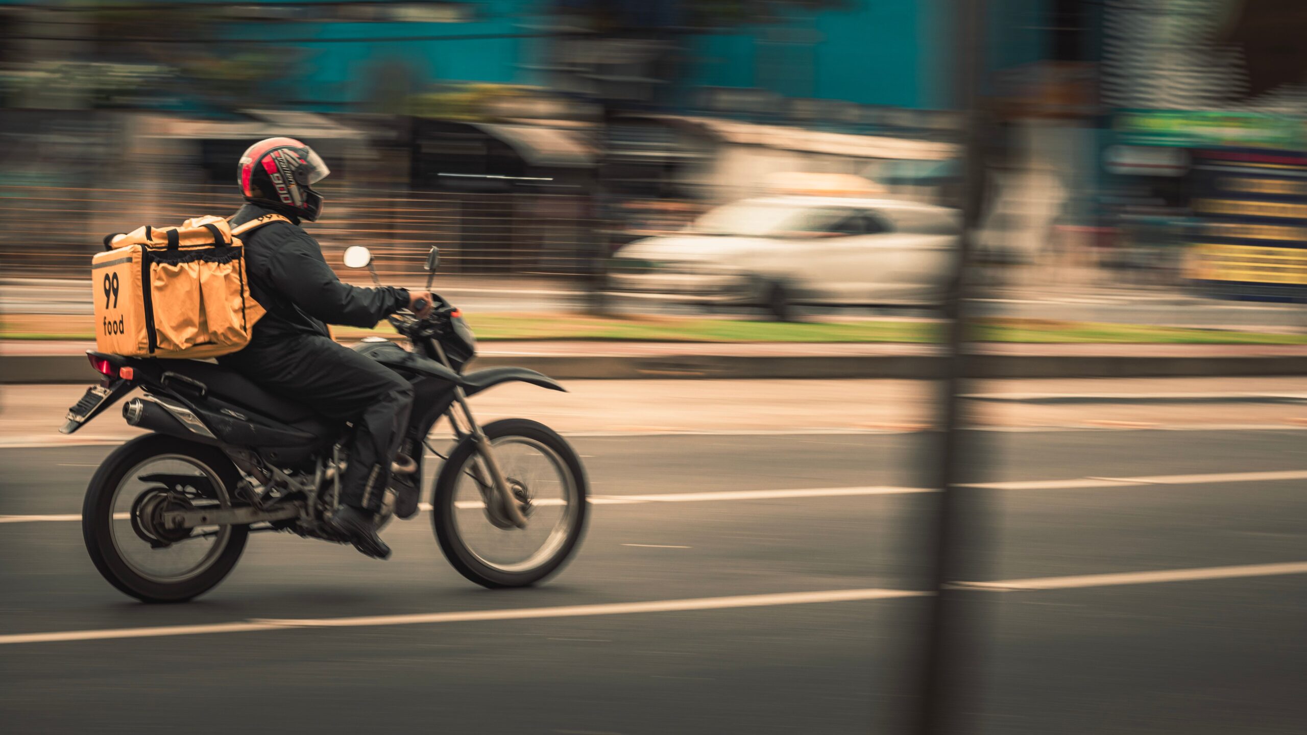 Motorcycle deliveryman speeds through city streets, showcasing fast food service.
